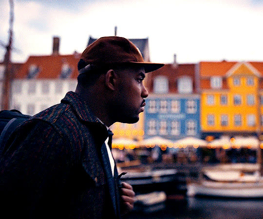 Marcus de perfil em Copenhague, com as casas coloridas de Nyhavn ao fundo e luz quente de fim de tarde